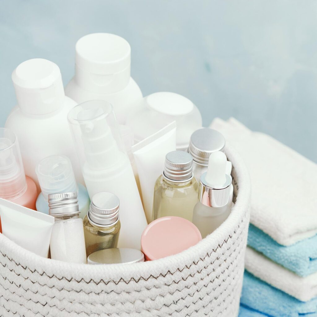 a basket filled with various skincare bottles and tubes next to neatly folded blue and white towels from RITA Corporation, global ingredient supplier